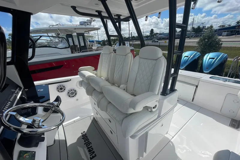Slide: The Image of 2022 Everglades 335 Center Console boat interior with white seating and steering wheel. - 22