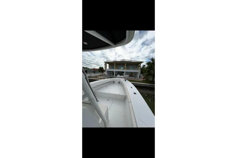 Slide: The Image of 2003 Jupiter 31 boat docked near a waterfront house under a cloudy sky. - 13