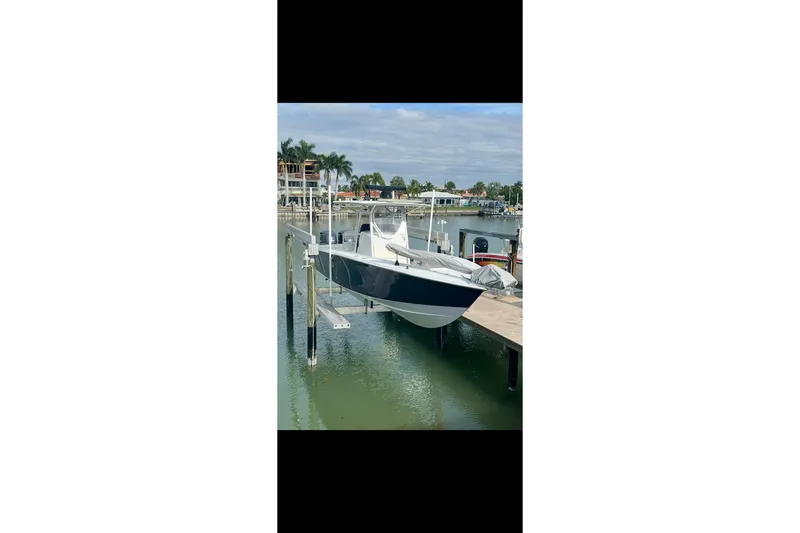 Slide: The Image of 2003 Jupiter 31 boat docked on a lift in a marina setting. - 2