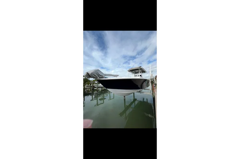 Slide: The Image of 2003 Jupiter 31 boat docked on calm water under a partly cloudy sky. - 3