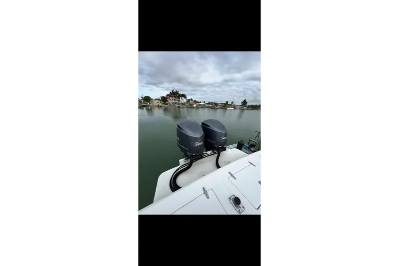 Slide: The Image of 2003 Jupiter 31 boat with dual outboard engines on a calm waterfront. - 5