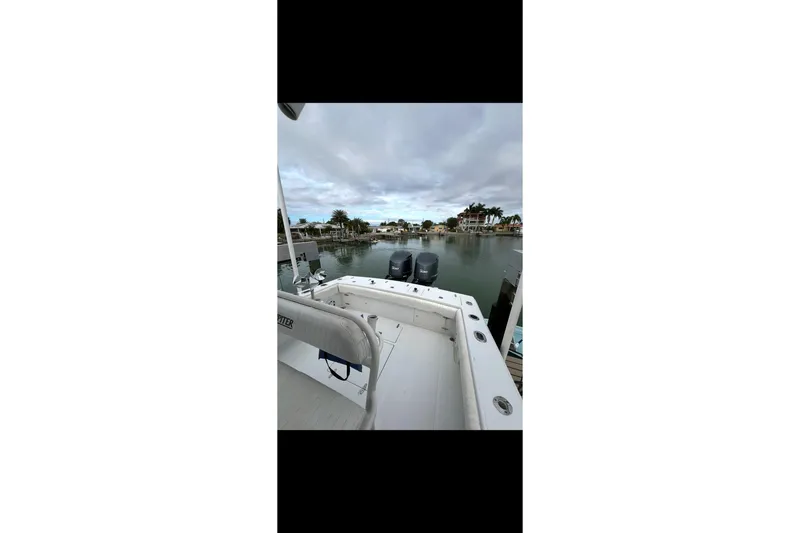 Slide: The Image of 2003 Jupiter 31 boat docked in a serene marina with dual outboard engines. - 7