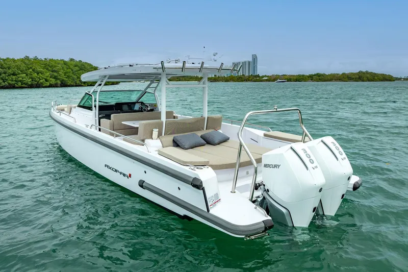 Slide: The Image of 2024 Axopar 37 Sun-Top boat with twin Mercury engines on turquoise water. - 4