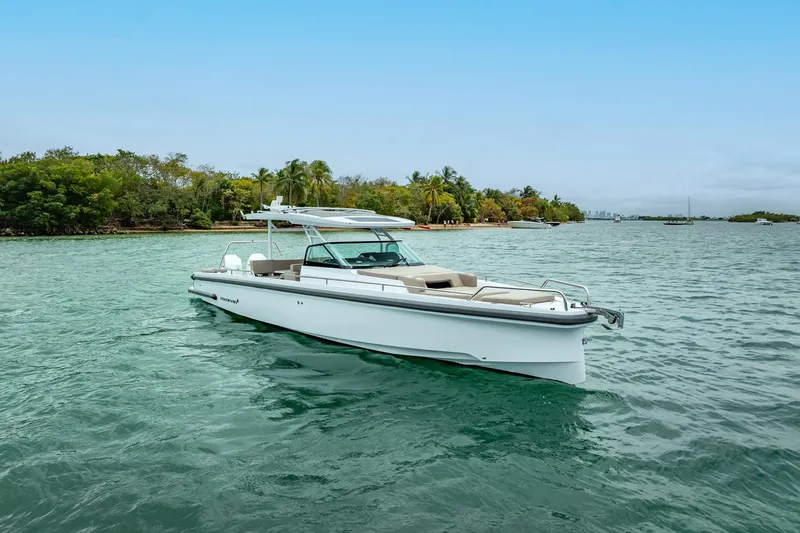 Slide: The Image of 2024 Axopar 37 Sun-Top boat cruising on clear waters near a tropical shoreline. - 6