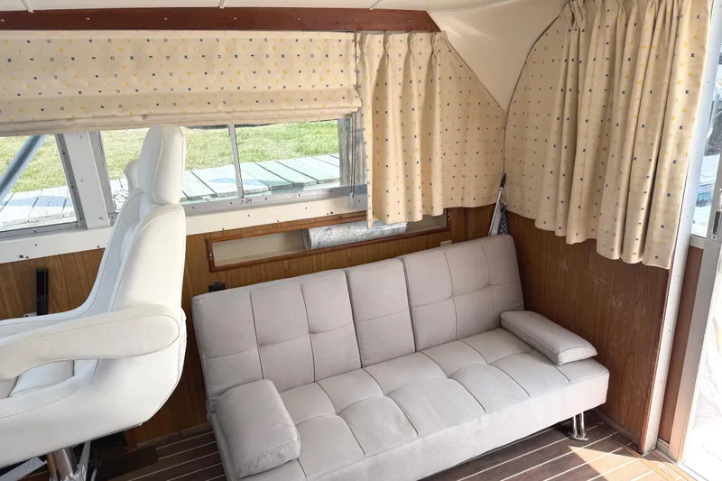 Slide: The Image of Interior of a 1974 Bertram 35 Convertible with sofa, captain's chair, and patterned curtains. - 11