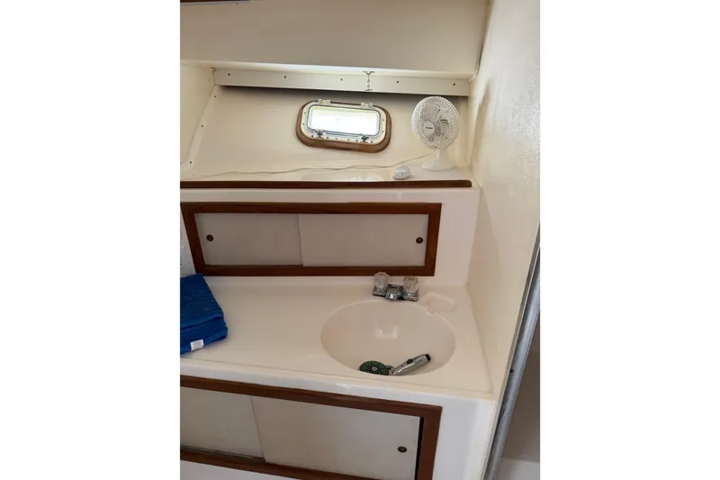 Slide: The Image of 1974 Bertram 35 Convertible boat bathroom with sink, fan, and storage cabinets. - 24