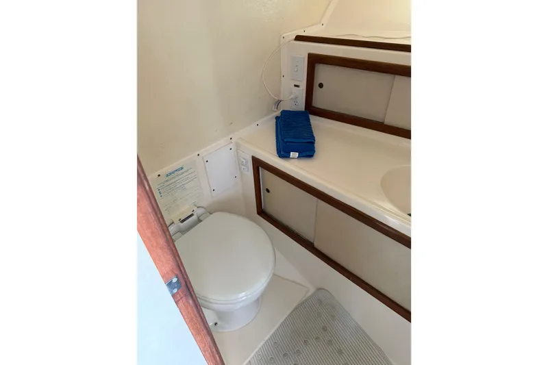 Slide: The Image of 1974 Bertram 35 Convertible boat bathroom with toilet, sink, and blue towel. - 25