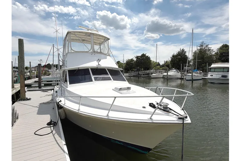 Slide: The Image of 1974 Bertram 35 Convertible yacht docked at a marina under a partly cloudy sky. - 3