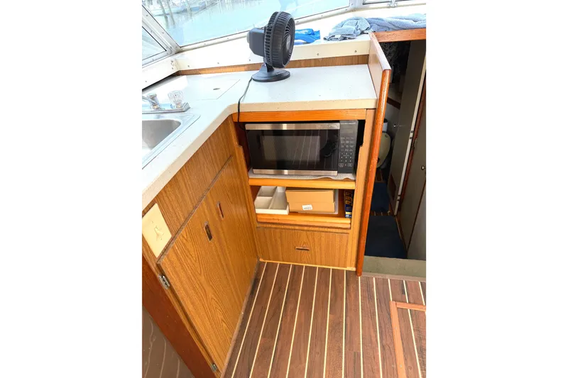Slide: The Image of 1974 Bertram 35 Convertible boat interior with microwave and wooden cabinetry. - 9