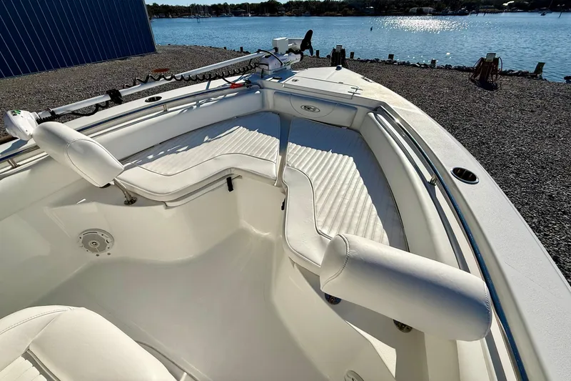 Slide: The Image of 2017 Sea Hunt Triton 225 boat with white seating, docked by a serene waterfront. - 10