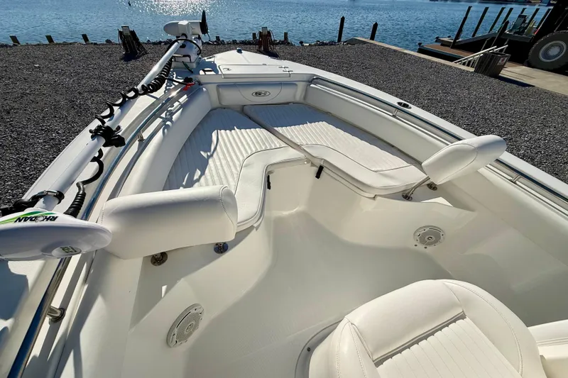 Slide: The Image of 2017 Sea Hunt Triton 225 boat interior with white seating, docked by the water. - 11