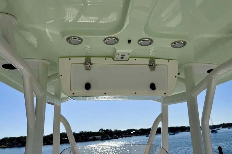 Slide: The Image of 2017 Sea Hunt Triton 225 boat canopy with storage compartment and lights, overlooking a scenic water view. - 19
