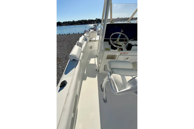 Slide: The Image of 2017 Sea Hunt Triton 225 boat interior with steering wheel, docked by a serene lake. - 27