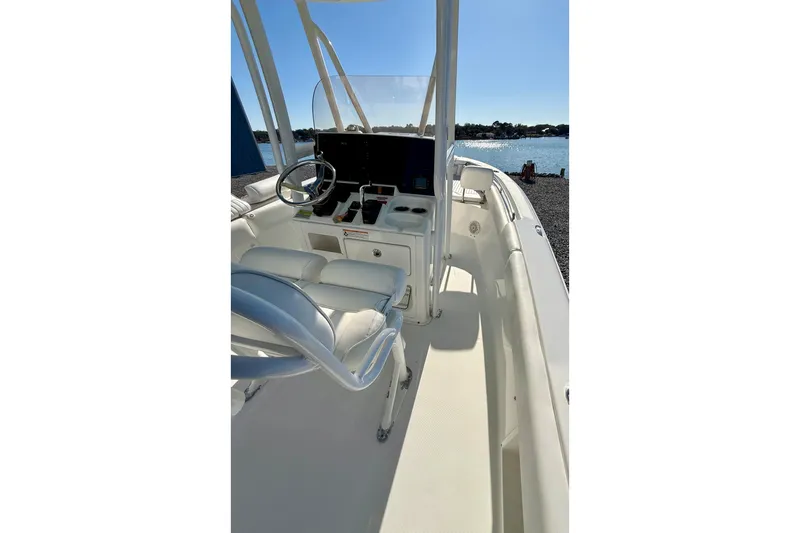 Slide: The Image of 2017 Sea Hunt Triton 225 boat interior with steering wheel and seating, near water. - 28