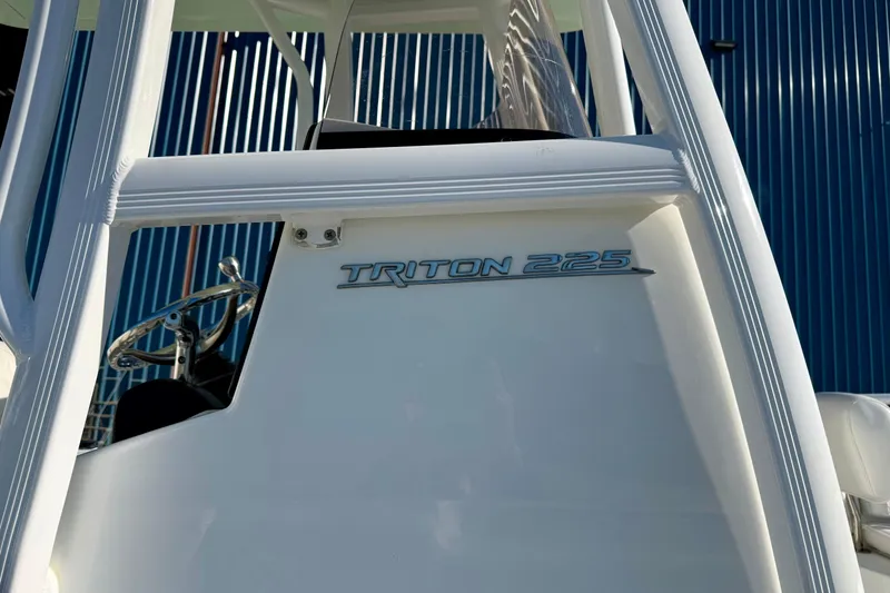 Slide: The Image of 2017 Sea Hunt Triton 225 boat, white exterior, steering wheel visible, against blue background. - 8