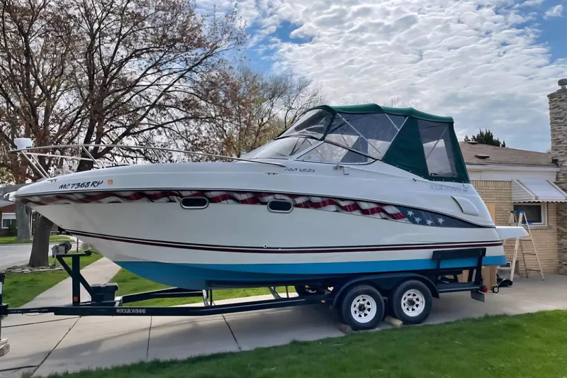 The Image of 2000 Four Winns 268 Vista boat on trailer, parked in driveway under cloudy sky. - 1