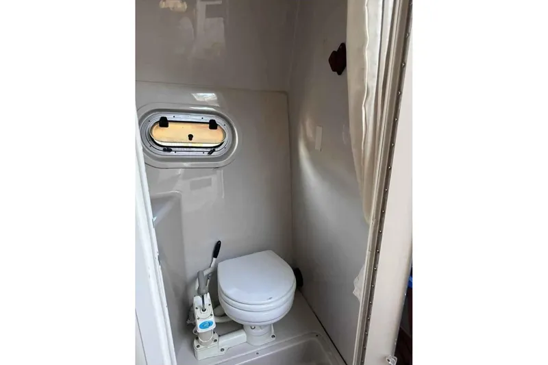 Slide: The Image of 2000 Four Winns 268 Vista boat bathroom with compact toilet and porthole window. - 14