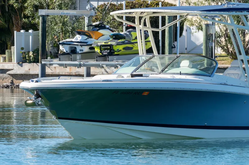 Slide: The Image of 2018 Chris-Craft Calypso 26 boat docked near jet skis, calm water. - 10