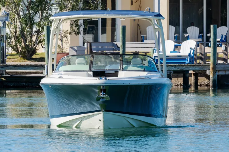 Slide: The Image of 2018 Chris-Craft Calypso 26 boat docked on calm water near a waterfront home. - 11