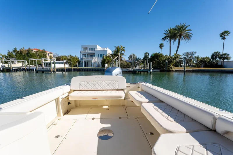Slide: The Image of 2018 Chris-Craft Calypso 26 boat on serene water with palm trees and modern homes. - 18