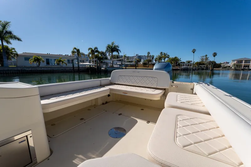 Slide: The Image of 2018 Chris-Craft Calypso 26 boat interior with luxurious seating, docked by palm trees. - 19