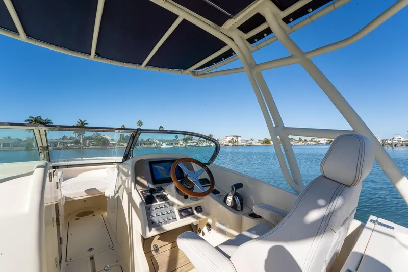 Slide: The Image of 2018 Chris-Craft Calypso 26 boat interior with steering wheel, overlooking serene waterfront. - 26