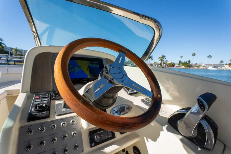 Slide: The Image of 2018 Chris-Craft Calypso 26 boat dashboard with wooden steering wheel and control panel. - 29