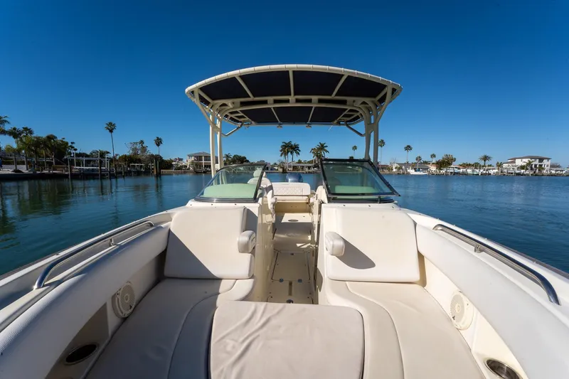Slide: The Image of 2018 Chris-Craft Calypso 26 boat on calm water, featuring spacious seating and canopy. - 36