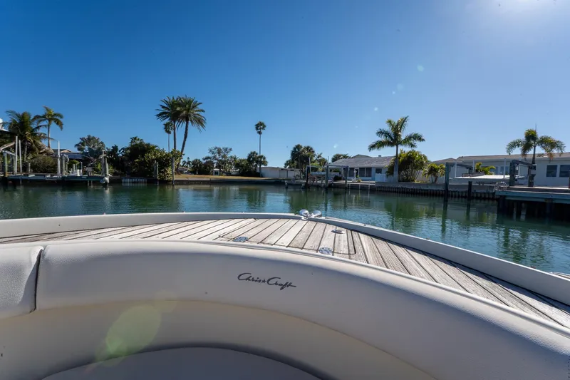 Slide: The Image of 2018 Chris-Craft Calypso 26 boat on calm water, surrounded by palm trees and waterfront homes. - 37