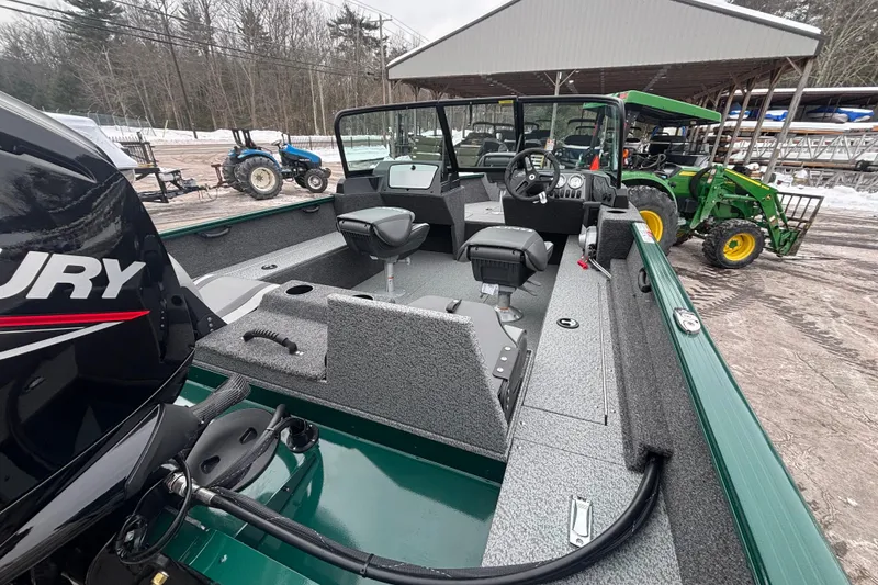 Slide: The Image of 2026 Lund 1650 Rebel XL Sport boat with Mercury engine, parked near tractors in snowy yard. - 10