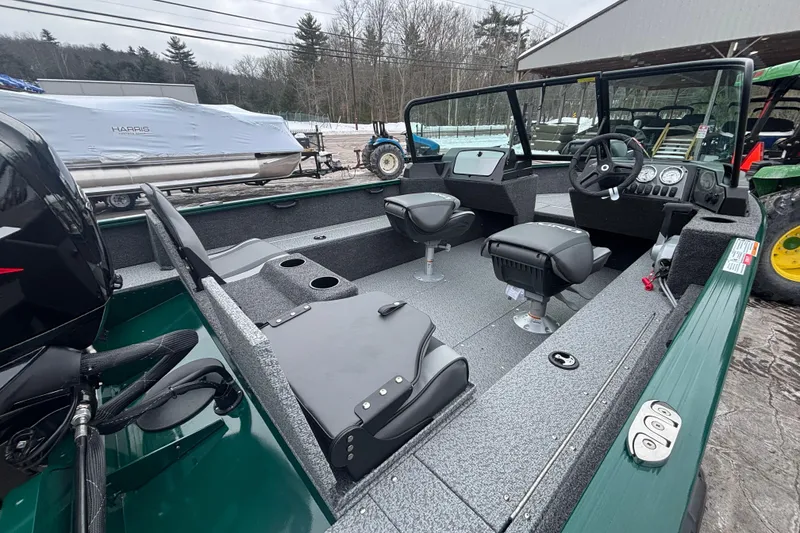 Slide: The Image of 2026 Lund 1650 Rebel XL Sport boat interior with seating and controls, parked outdoors. - 11