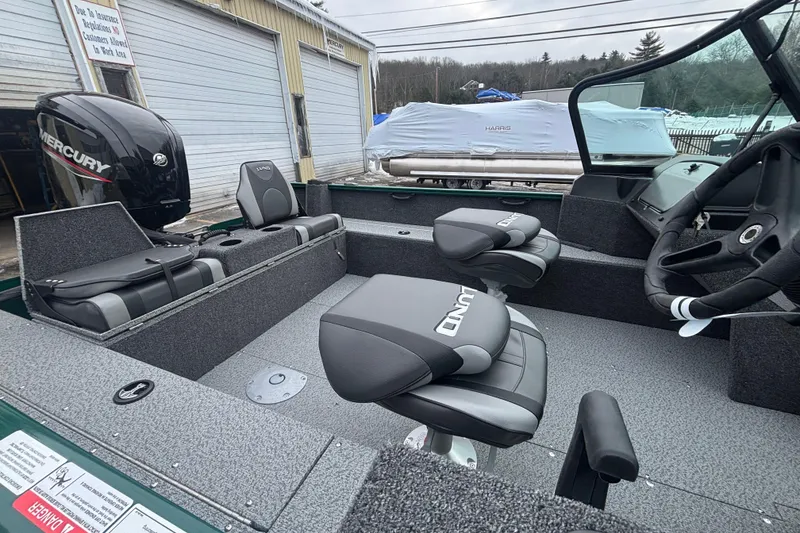 Slide: The Image of 2026 Lund 1650 Rebel XL Sport boat interior with Mercury engine, featuring comfortable seating and steering console. - 14