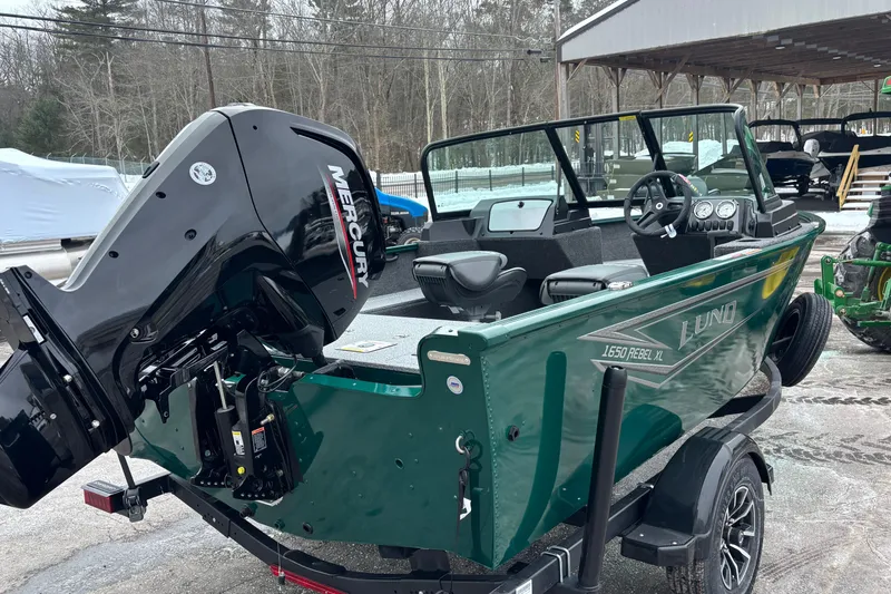 Slide: The Image of 2026 Lund 1650 Rebel XL Sport boat with Mercury outboard motor, parked outdoors. - 3