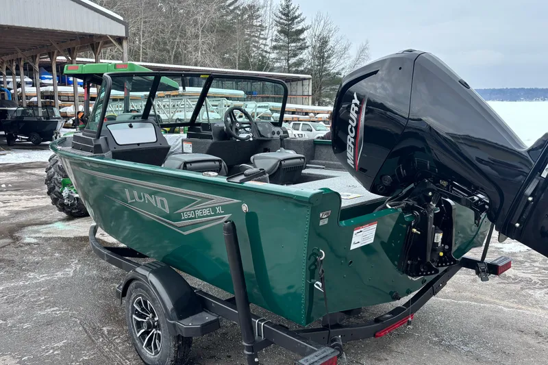 Slide: The Image of 2026 Lund 1650 Rebel XL Sport boat with Mercury engine, parked outdoors. - 4