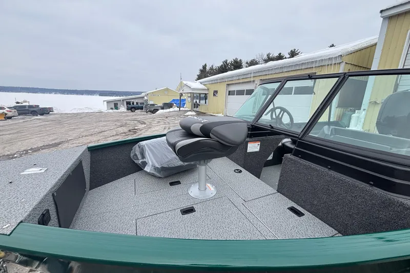 Slide: The Image of 2026 Lund 1650 Rebel XL Sport boat with seating, docked near snowy landscape. - 6