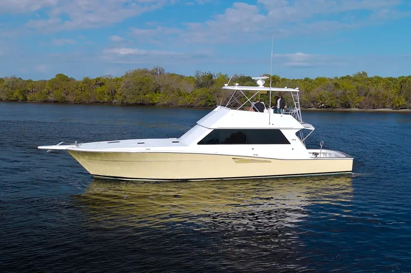 Slide: The Image of 1990 Viking 53 Convertible yacht cruising on a calm river under a clear blue sky. - 102