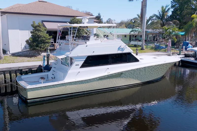 Slide: The Image of 1990 Viking 53 Convertible yacht docked by waterfront home, surrounded by palm trees. - 13