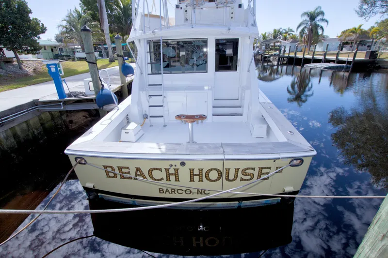 Slide: The Image of 1990 Viking 53 Convertible yacht named "Beach House" docked in a serene marina. - 16