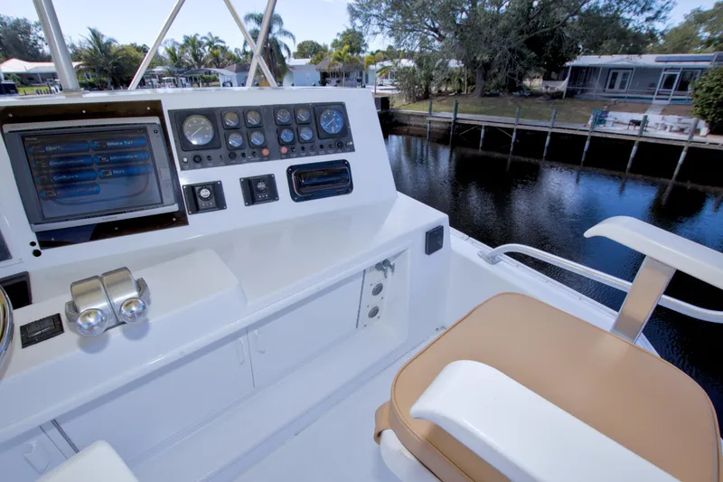 Slide: The Image of 1990 Viking 53 Convertible yacht helm with controls and navigation display by a serene waterfront. - 29