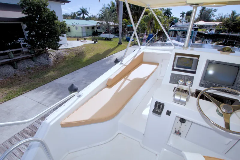 Slide: The Image of 1990 Viking 53 Convertible yacht helm with navigation equipment and seating, docked near waterfront homes. - 31