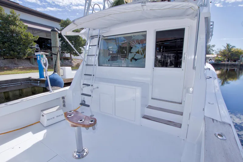 Slide: The Image of 1990 Viking 53 Convertible yacht deck with ladder and seating, docked by a serene waterfront. - 37