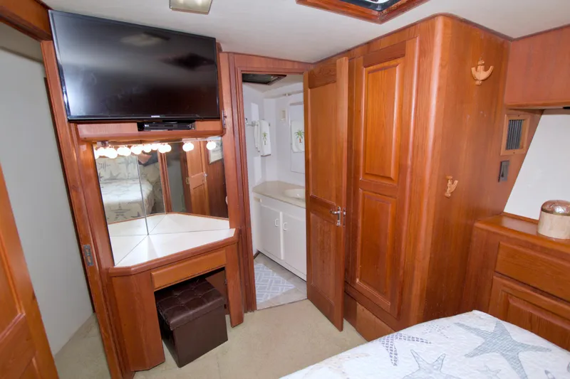 Slide: The Image of 1990 Viking 53 Convertible yacht interior with wood cabinetry, TV, vanity, and bathroom entrance. - 57