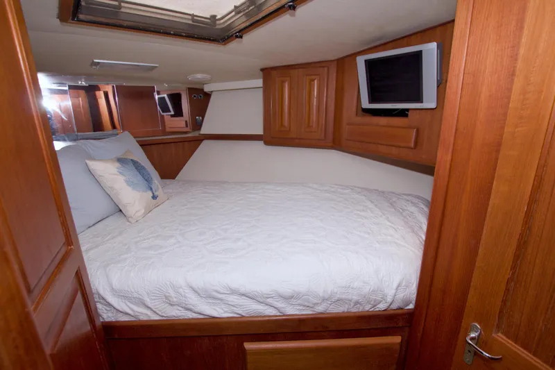 Slide: The Image of Cozy cabin interior of 1990 Viking 53 Convertible yacht with wood paneling and bedding. - 68
