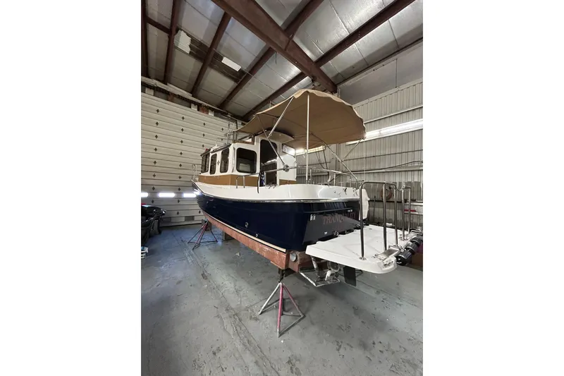 Slide: The Image of 2017 Ranger Tugs R-25 SC boat in storage, featuring a canopy and blue hull. - 4