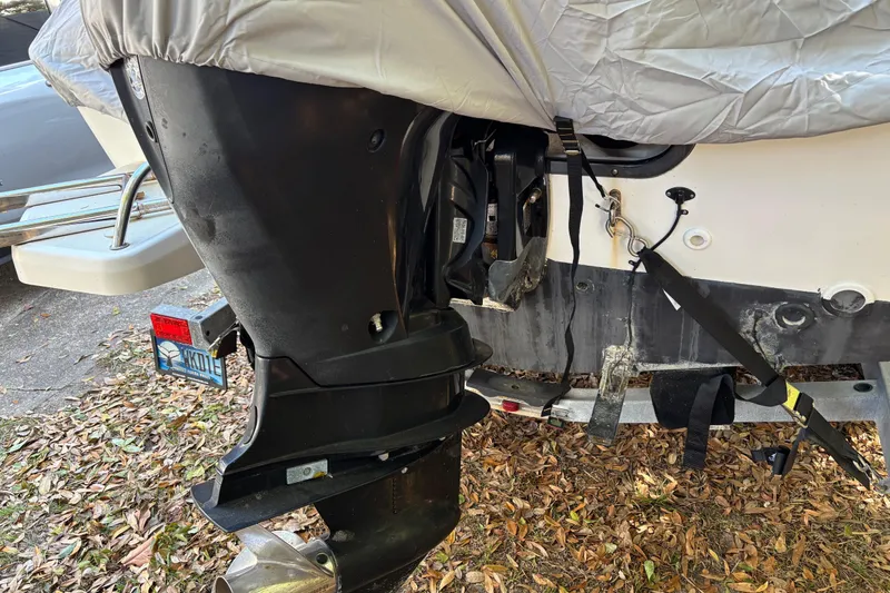 Slide: The Image of 2015 Boston Whaler 190 Outrage boat engine covered, parked on trailer with fallen leaves. - 12