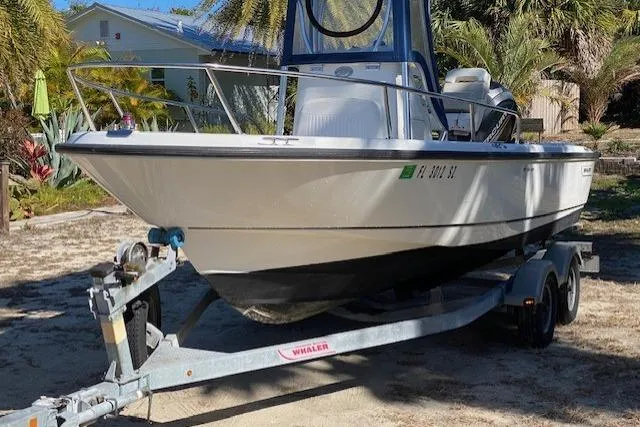 Slide: The Image of 2015 Boston Whaler 190 Outrage boat on trailer, parked outdoors with tropical plants. - 3