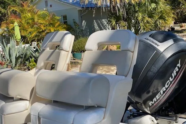Slide: The Image of 2015 Boston Whaler 190 Outrage boat seats with Mercury engine, surrounded by lush greenery. - 6