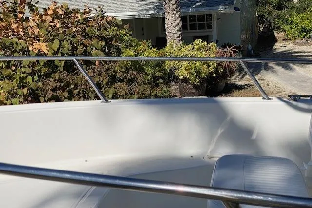 Slide: The Image of 2015 Boston Whaler 190 Outrage boat near a house with lush greenery. - 7