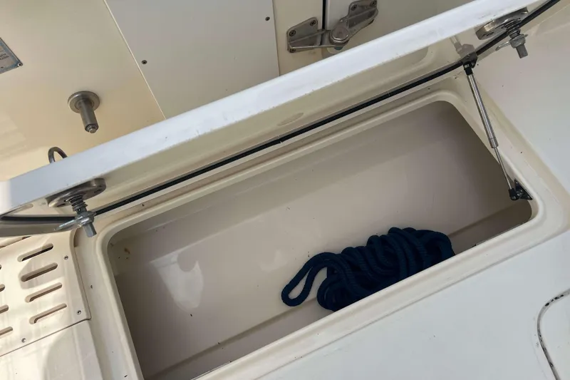 Slide: The Image of Open storage compartment on 2021 Scout 305 LXF boat with coiled blue rope. - 18