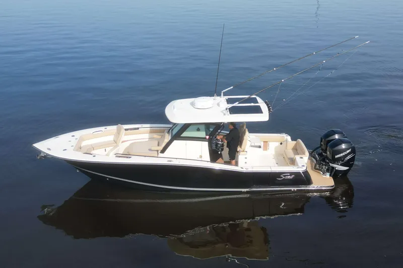 Slide: The Image of 2021 Scout 305 LXF boat on calm water, featuring dual Mercury engines. - 2